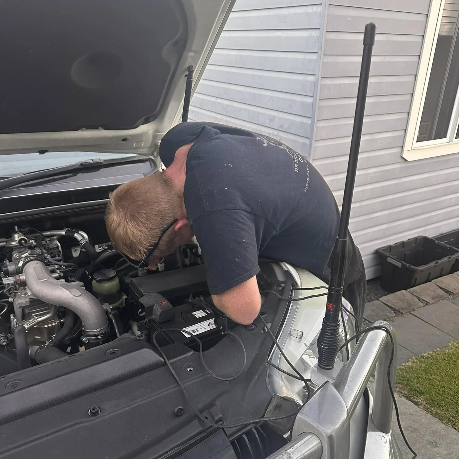 Mechanic working on a van engine beside a caravan